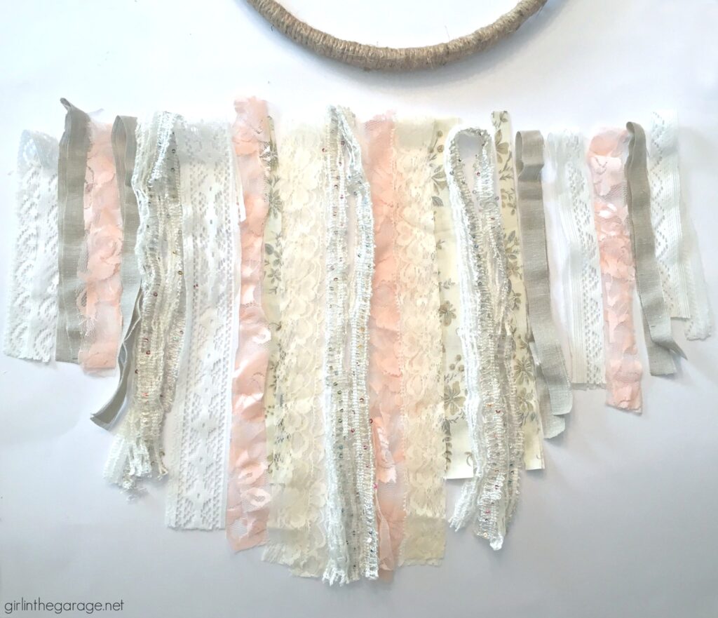 Make a stunning DIY embroidery hoop wreath with lace, ribbon, and fabric scraps. Add some flowers for fun! DIY decor ideas by Girl in the Garage