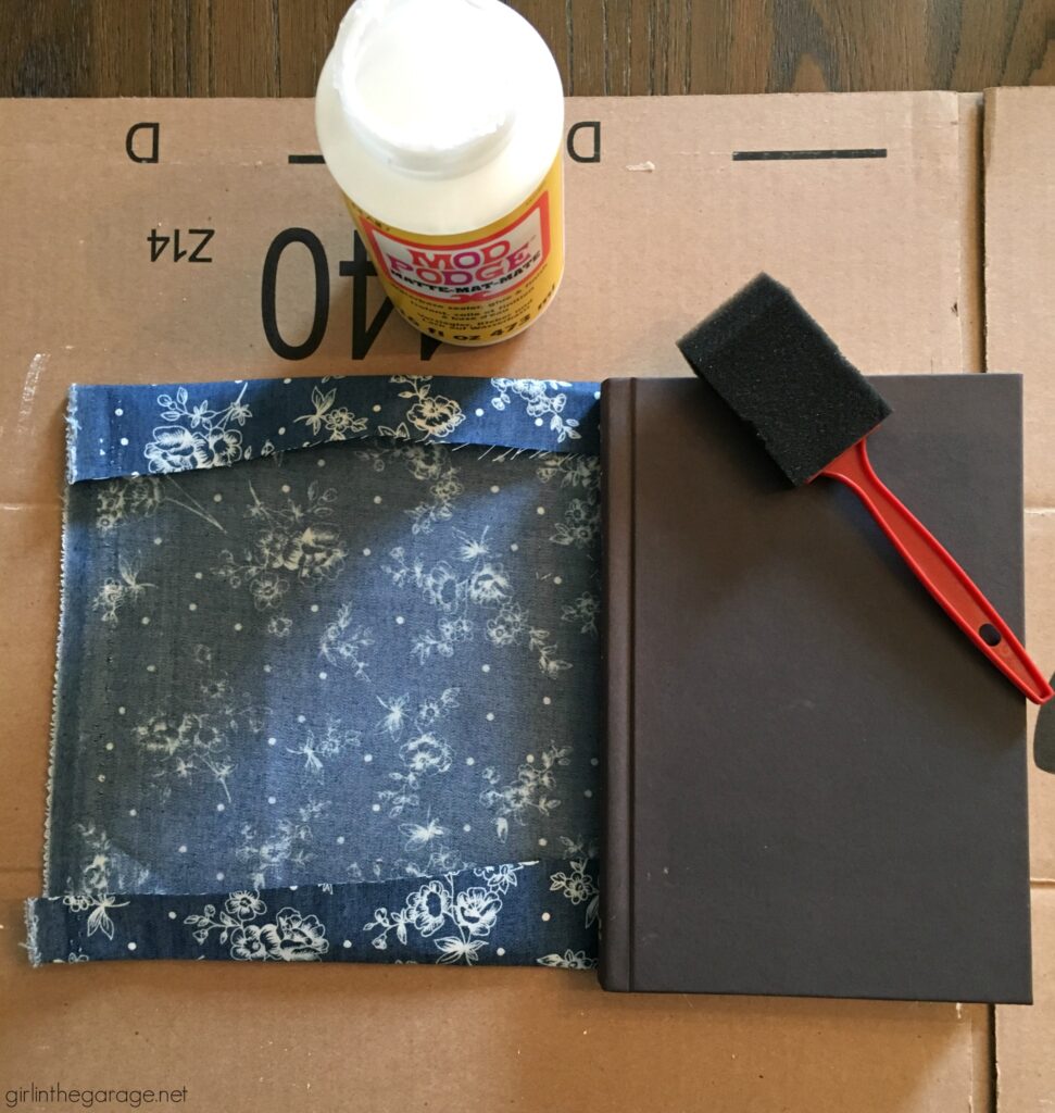 Learn how to decoupage fabric onto books and create gorgeous budget-friendly DIY home decor with this step by step tutorial from Girl in the Garage.