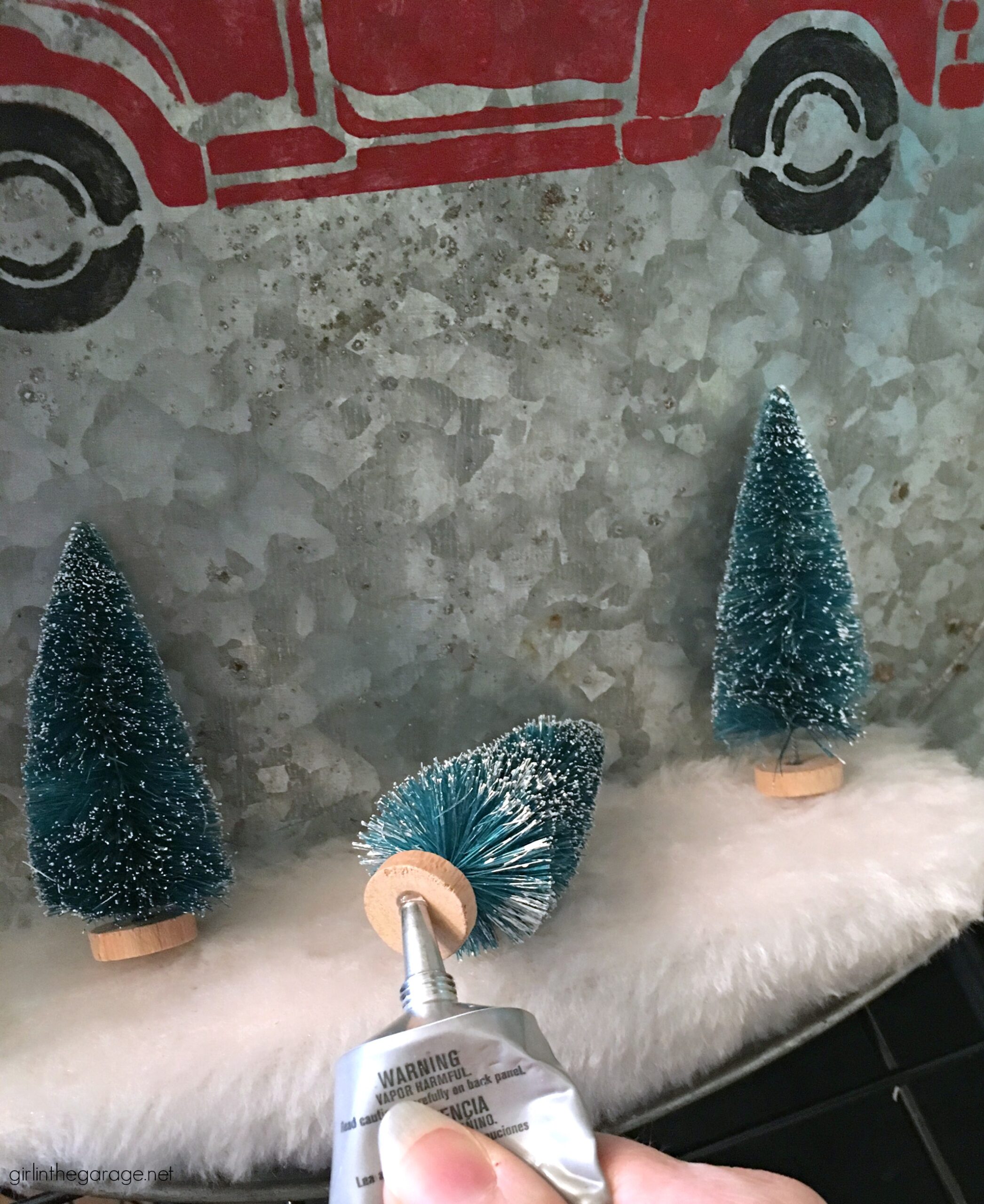 Make a DIY Christmas wreath from a repurposed metal tray - an adorable Christmas decor idea with stenciled truck and miniature bottle brush trees! By Girl in the Garage