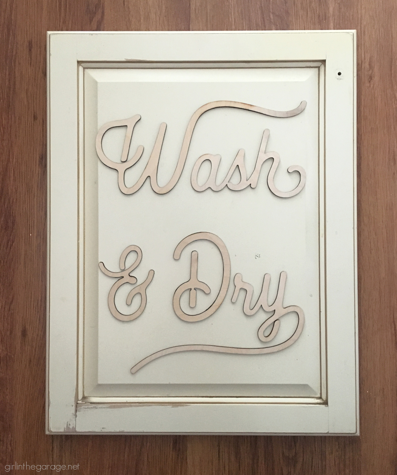 Learn how to repurpose an old cabinet door into an adorable DIY laundry room sign with grain sack stripes! By Girl in the Garage