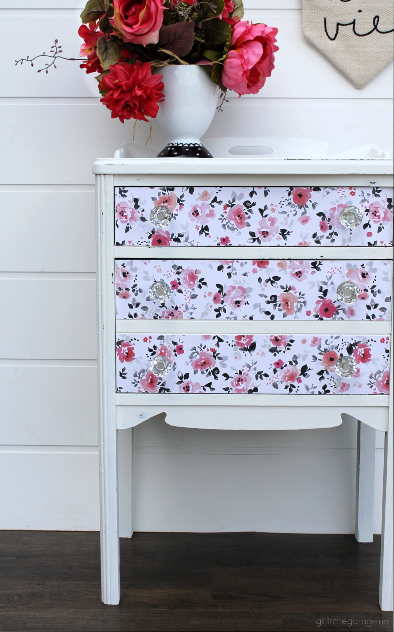 How to paint a vintage nightstand white and add charming decoupage poster board on the drawers. By Girl in the Garage